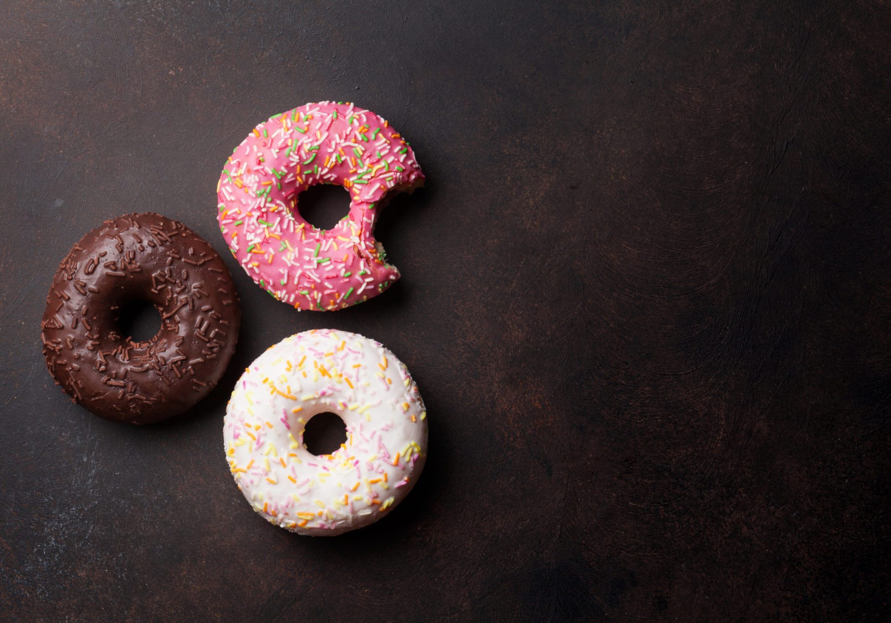 Colorful donuts on stone table. Top view with copy space