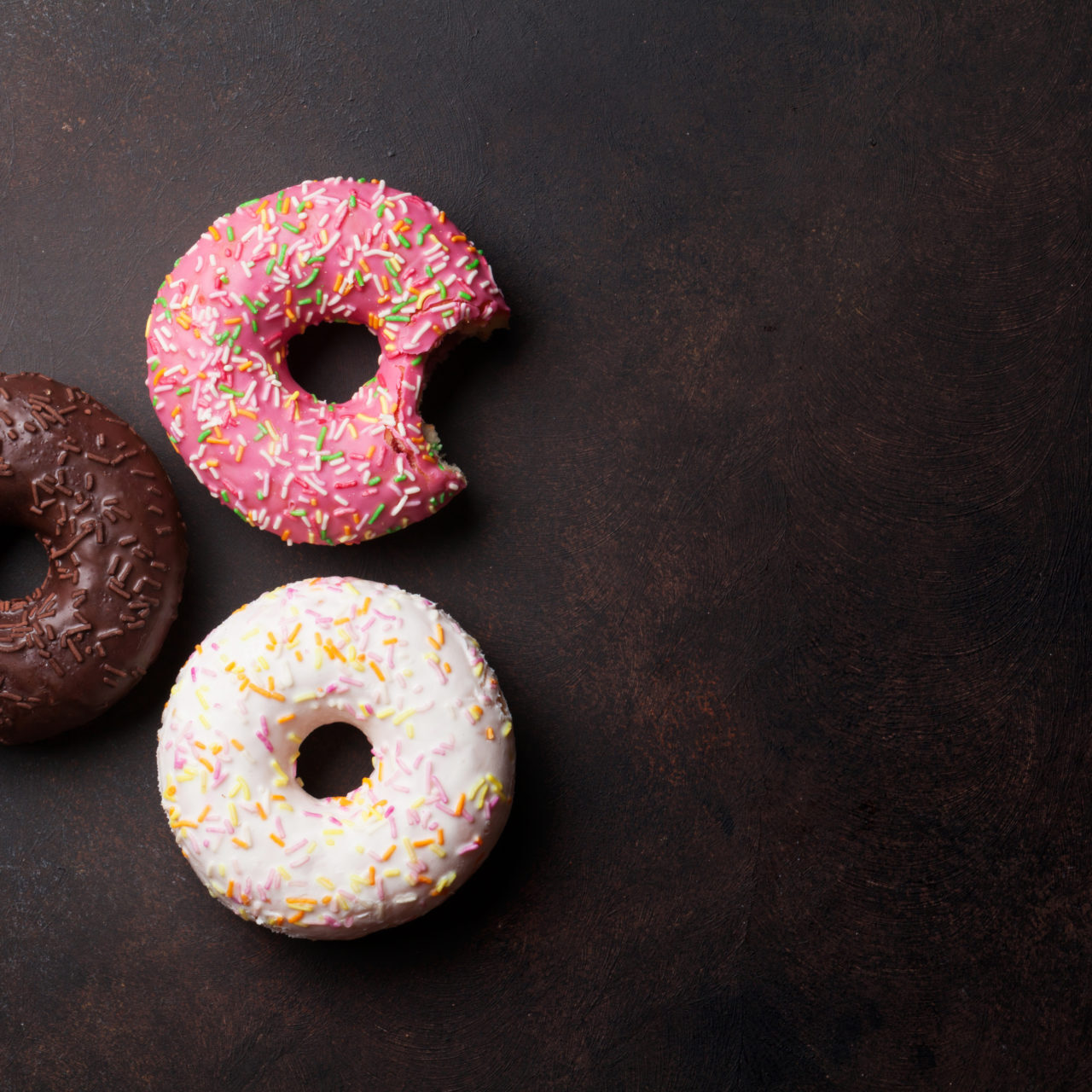 Colorful donuts on stone table. Top view with copy space