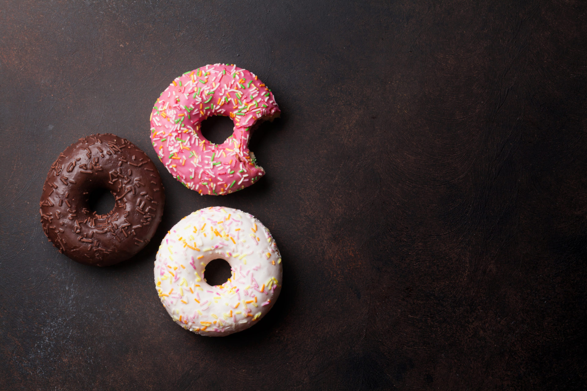 Colorful donuts on stone table. Top view with copy space